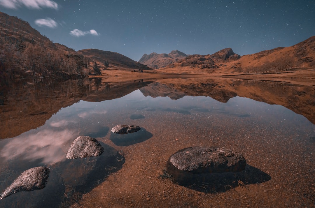 a lake surrounded by mountains under a night sky