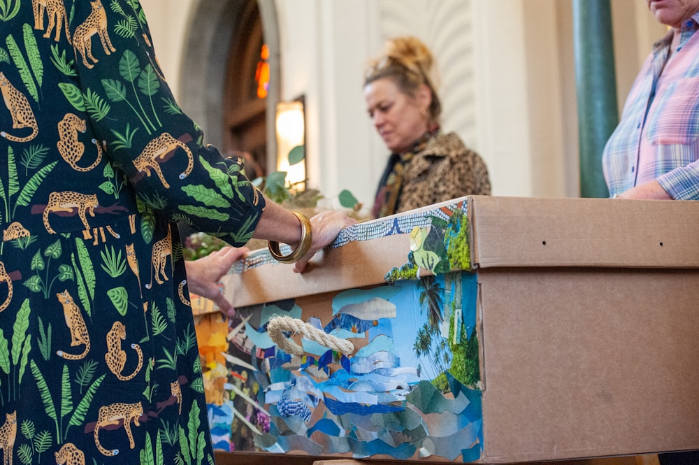 a woman standing next to a box with a painting on it