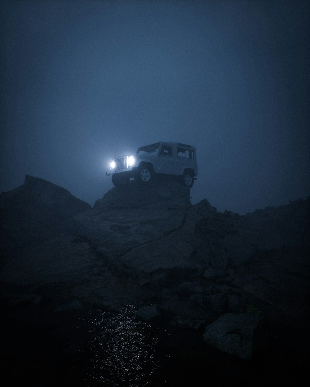 a jeep driving up a hill in the fog