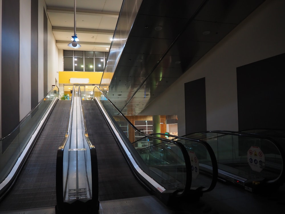 an escalator in a large building with a light hanging from the ceiling