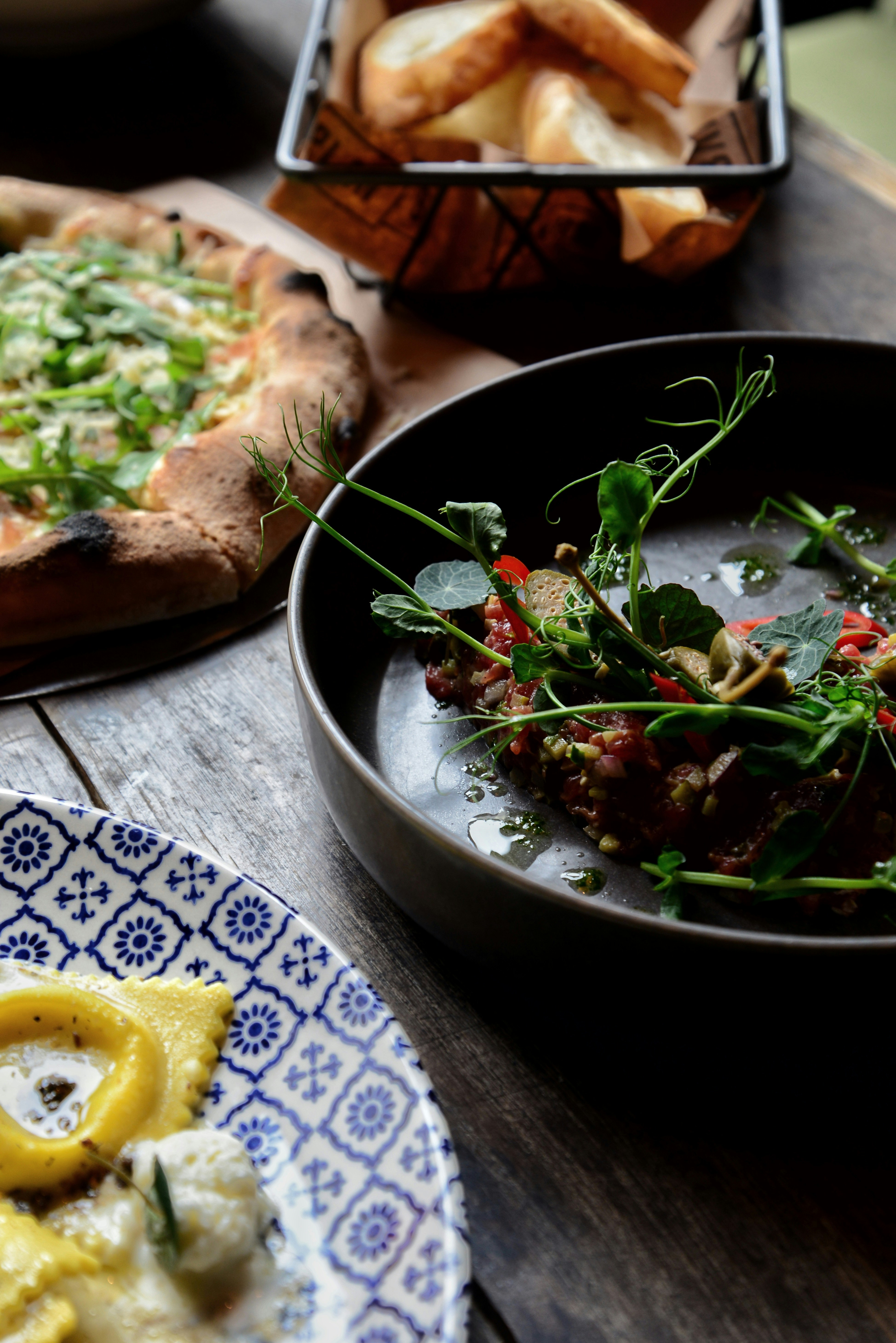 a table topped with plates of food and a pizza
