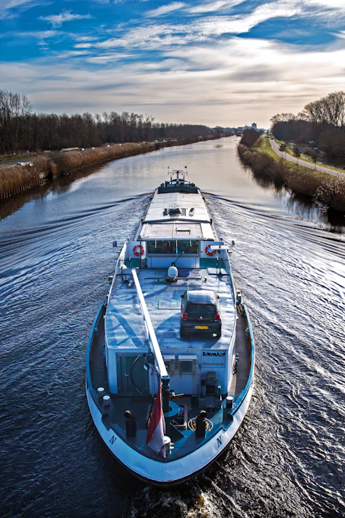 a boat traveling down a river next to a forest