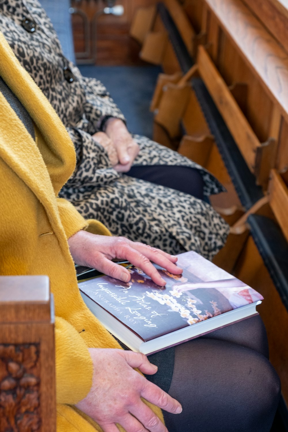 Una donna in un cappotto giallo sta leggendo un libro