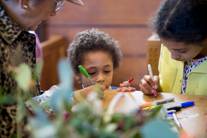 A calm family moment captured in muted sage tones, with children engaged in creative play.
