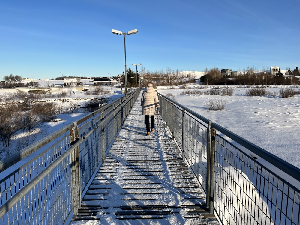 a woman walking across a bridge in the snow