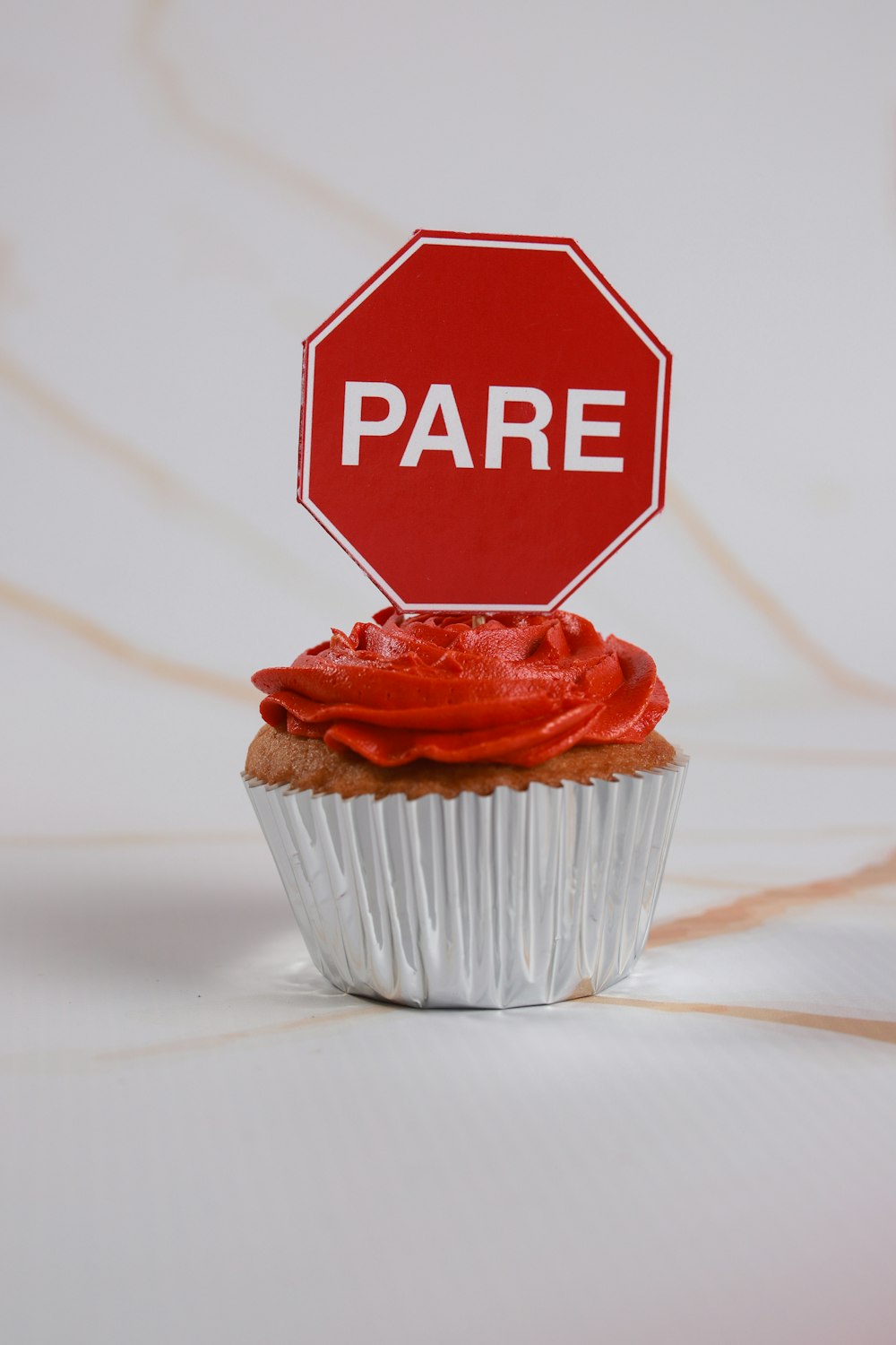 a cupcake with a red frosting sitting in front of a stop sign