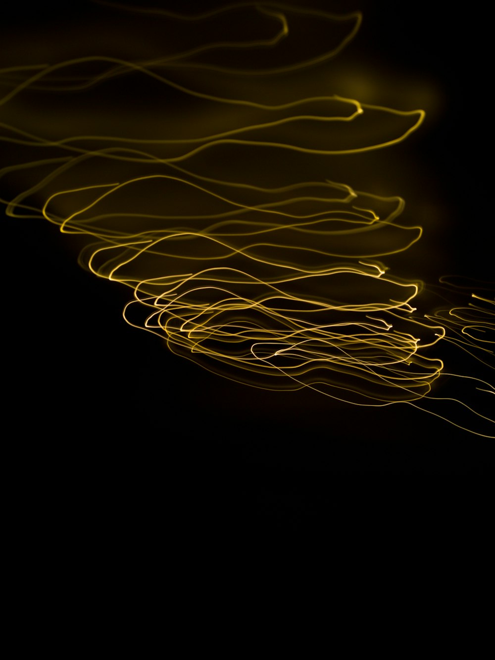 a long exposure photo of yellow lines on a black background