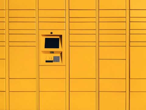 A series of yellow lockers with a digital interface and keypad located centrally on one of the compartments. The lockers have a modern and minimalist design with evenly spaced horizontal and vertical lines.