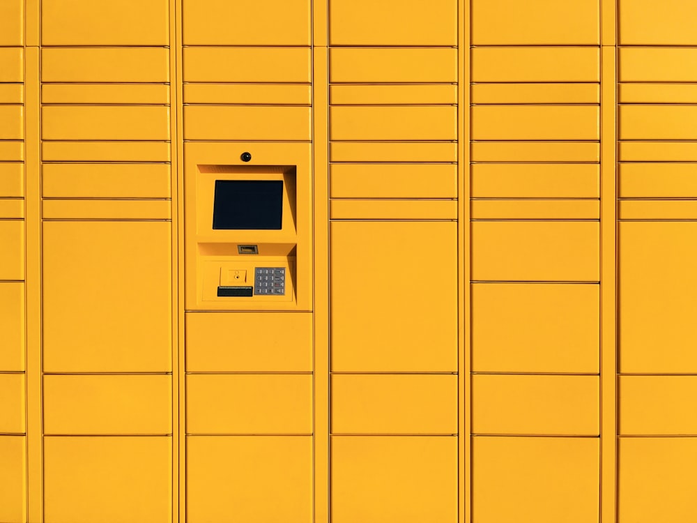uma parede amarela com um telefone público nela