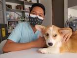 a man wearing a face mask sitting next to a dog