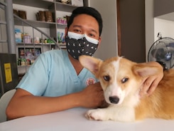 a man wearing a face mask sitting next to a dog