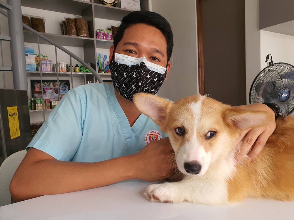 Ein Mann mit Gesichtsmaske sitzt neben einem Hund