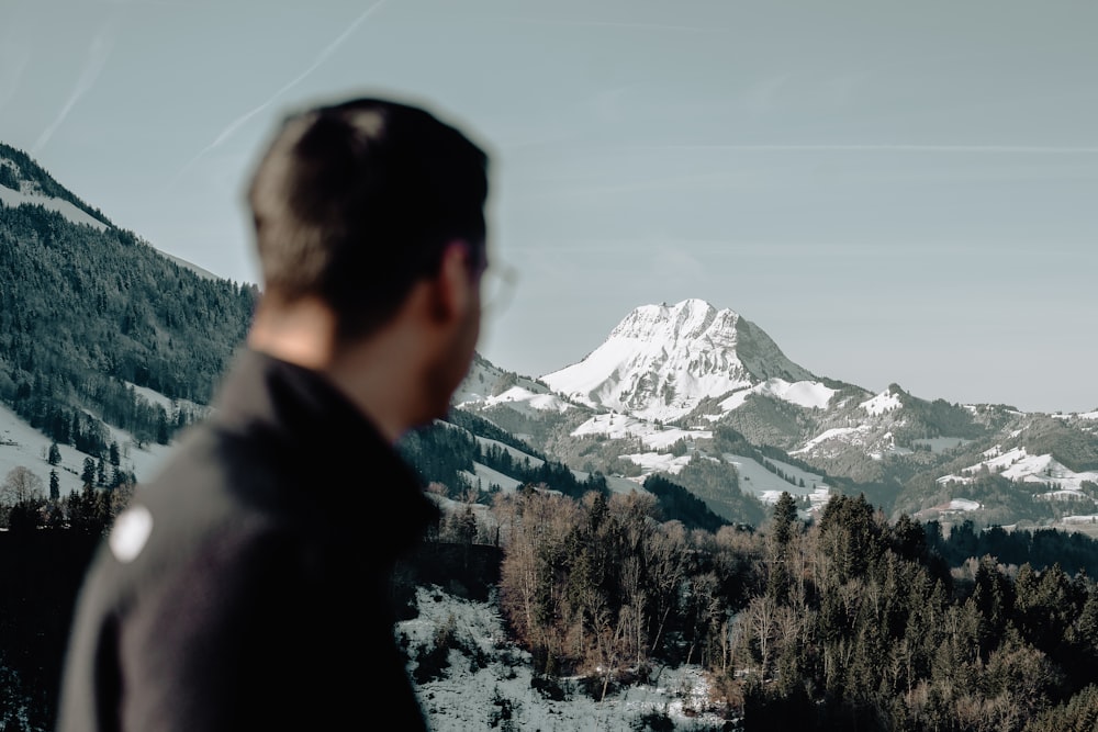 a man standing in front of a snow covered mountain