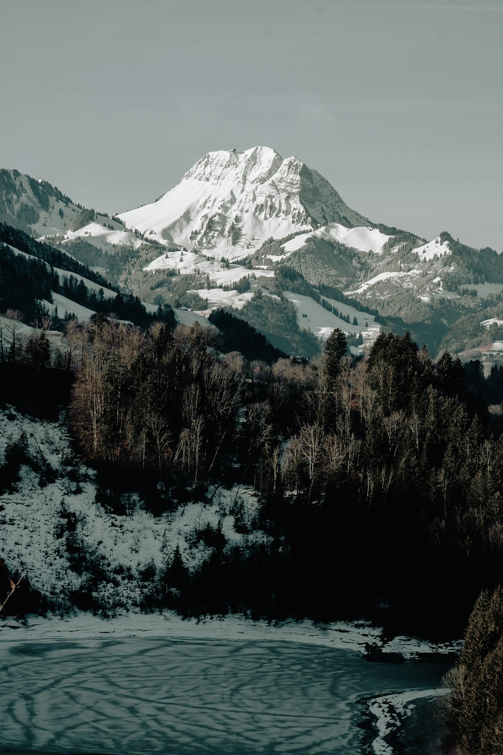 a snow covered mountain with a lake in the foreground