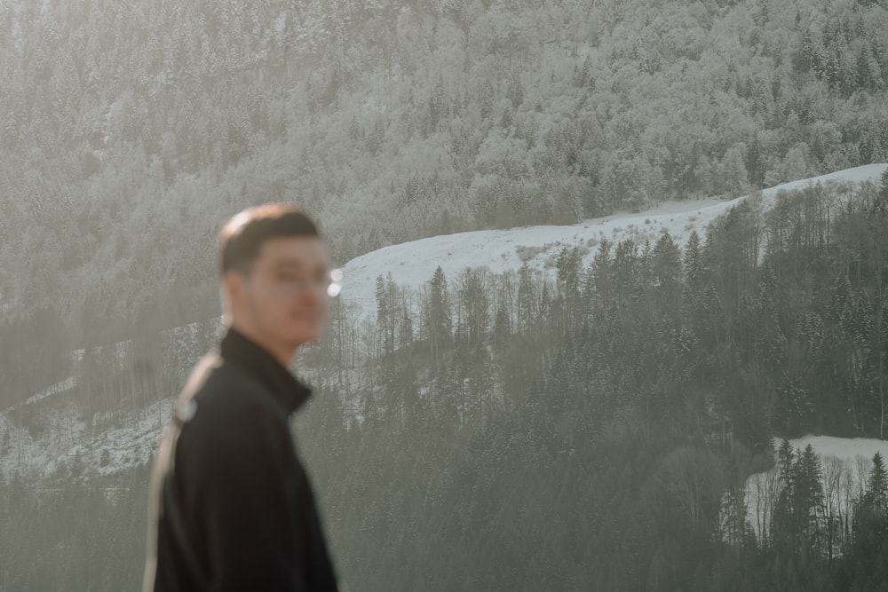 a man standing in front of a snow covered mountain