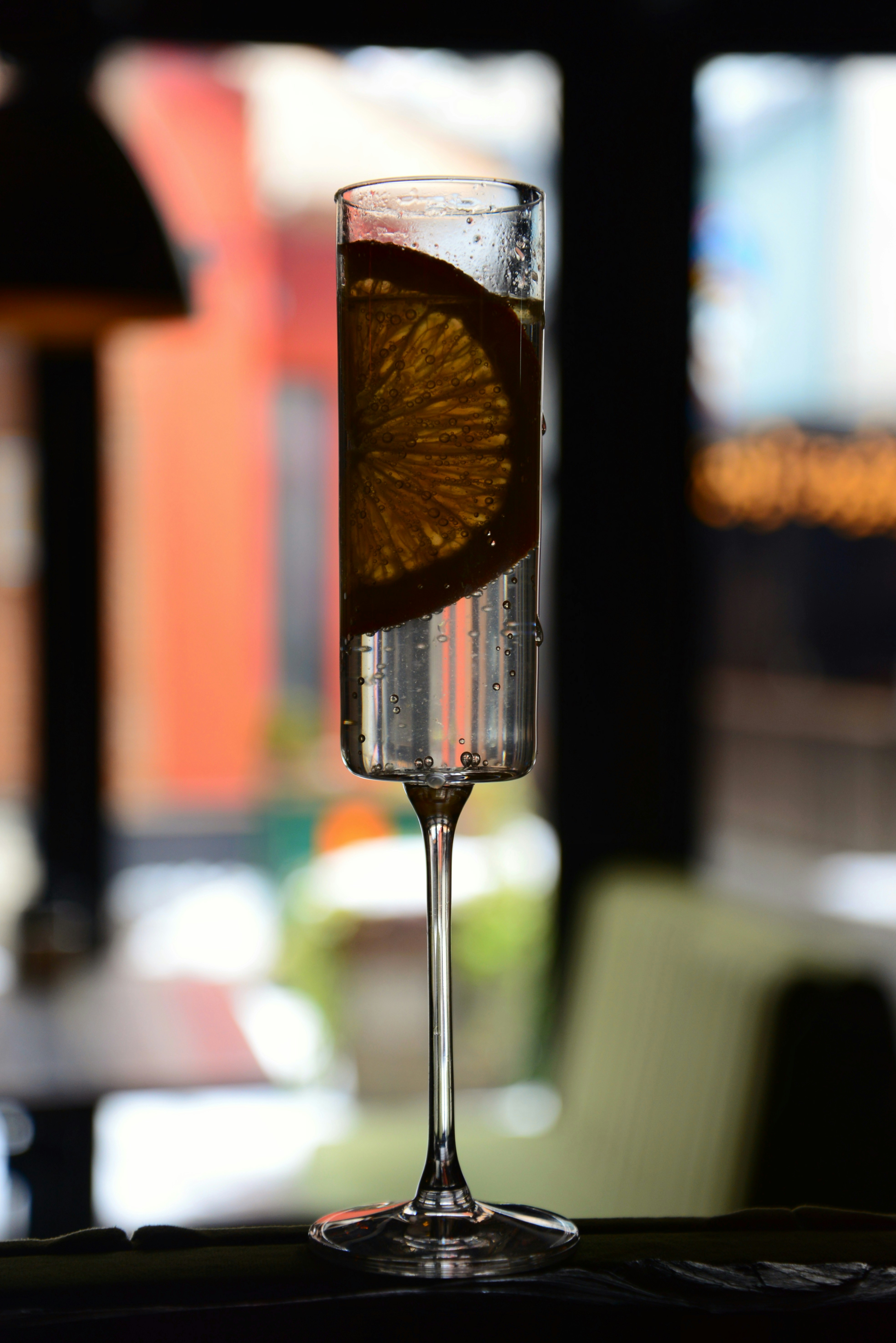 a glass of wine with a slice of orange in it