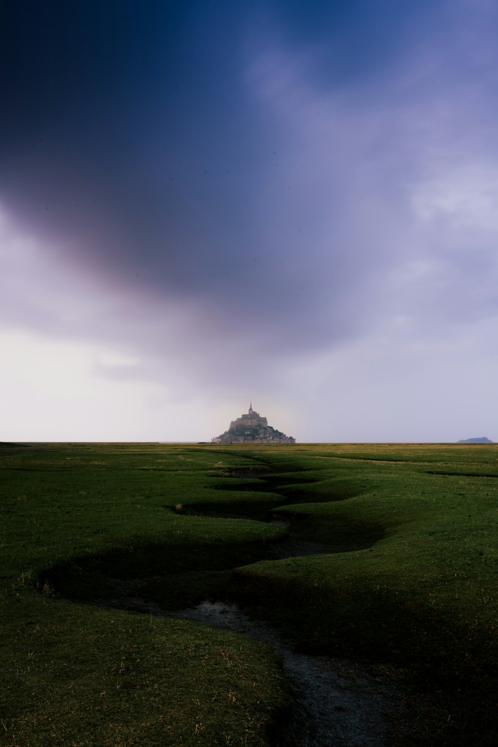 a grassy field with a small hill in the distance