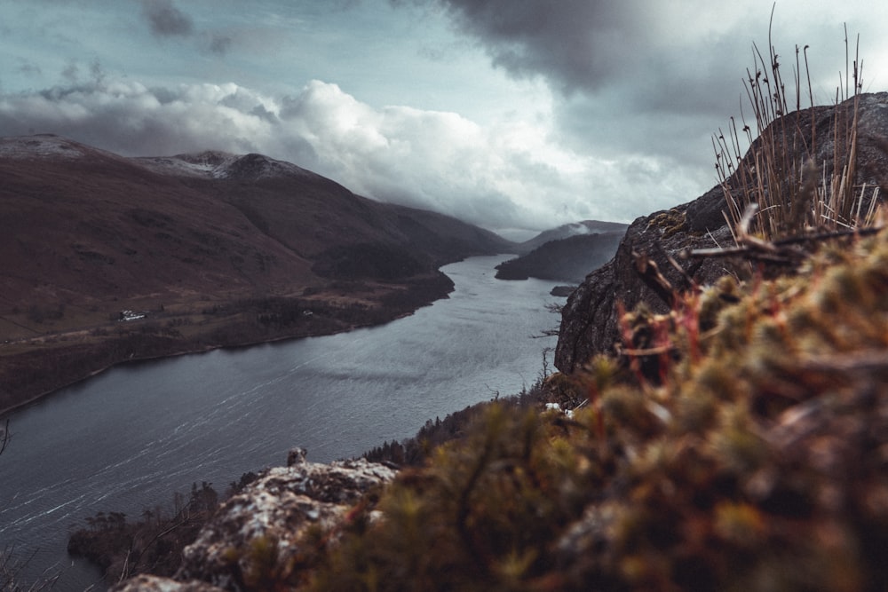 a body of water surrounded by mountains under a cloudy sky