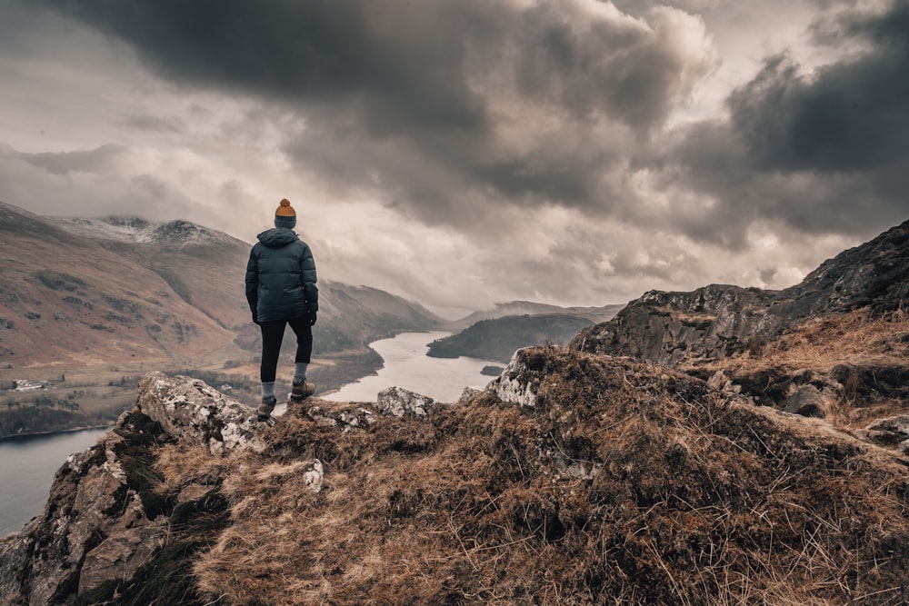 Un uomo in piedi sulla cima di una montagna che domina un lago