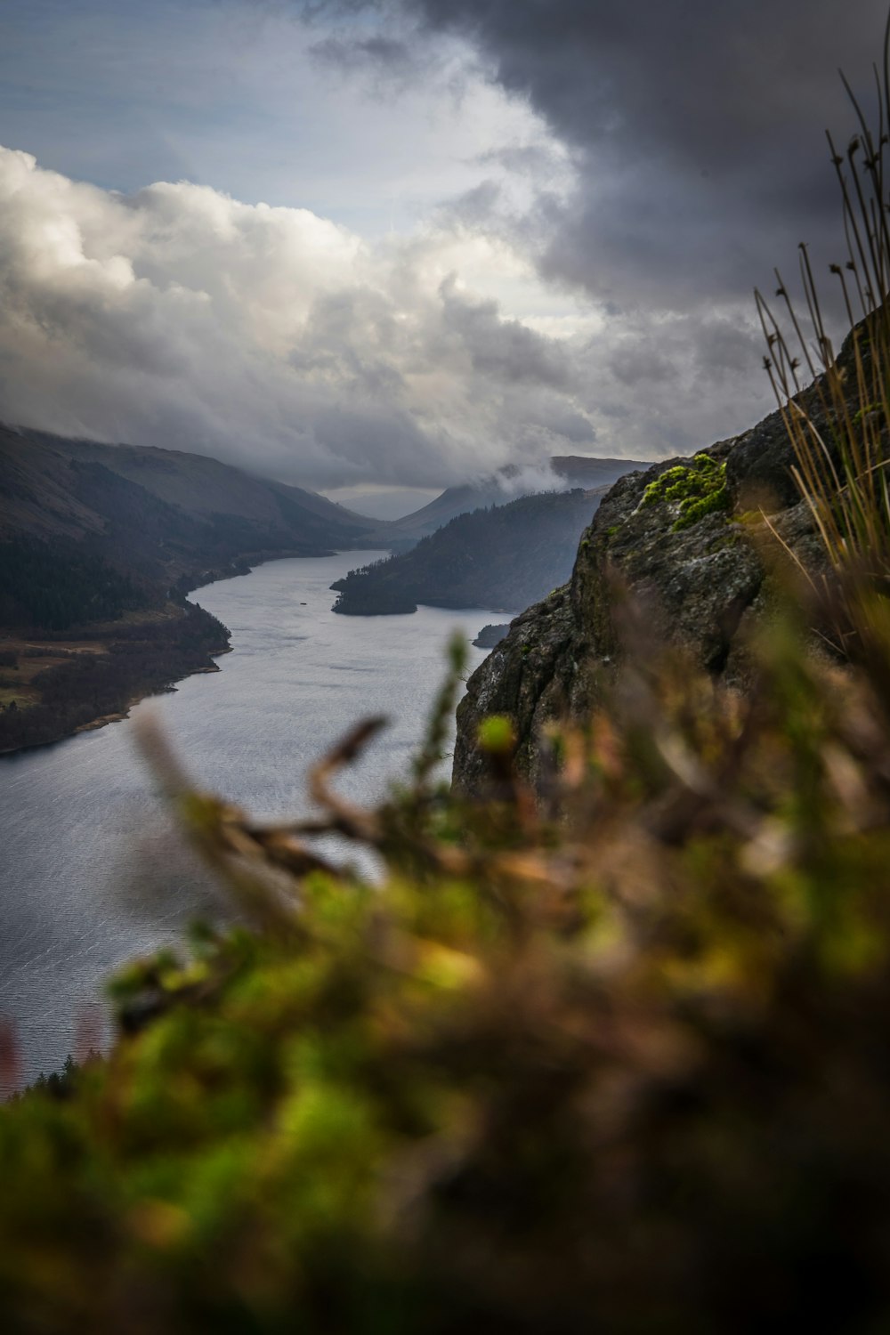 a body of water surrounded by mountains under a cloudy sky