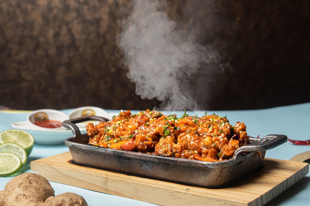 a pan filled with food sitting on top of a wooden cutting board