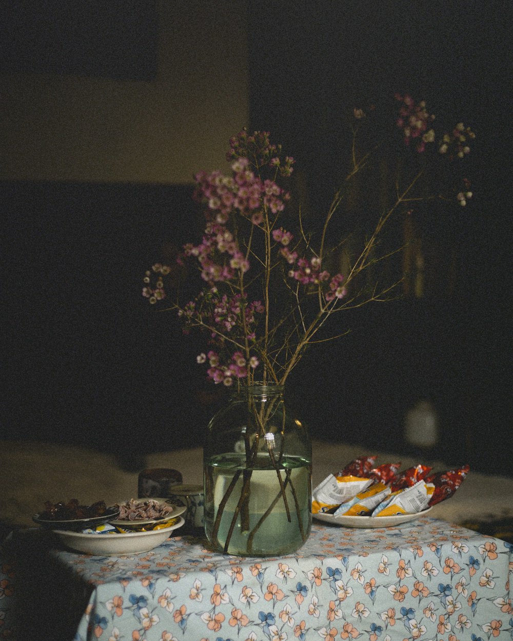 a table topped with plates of food and a vase filled with flowers