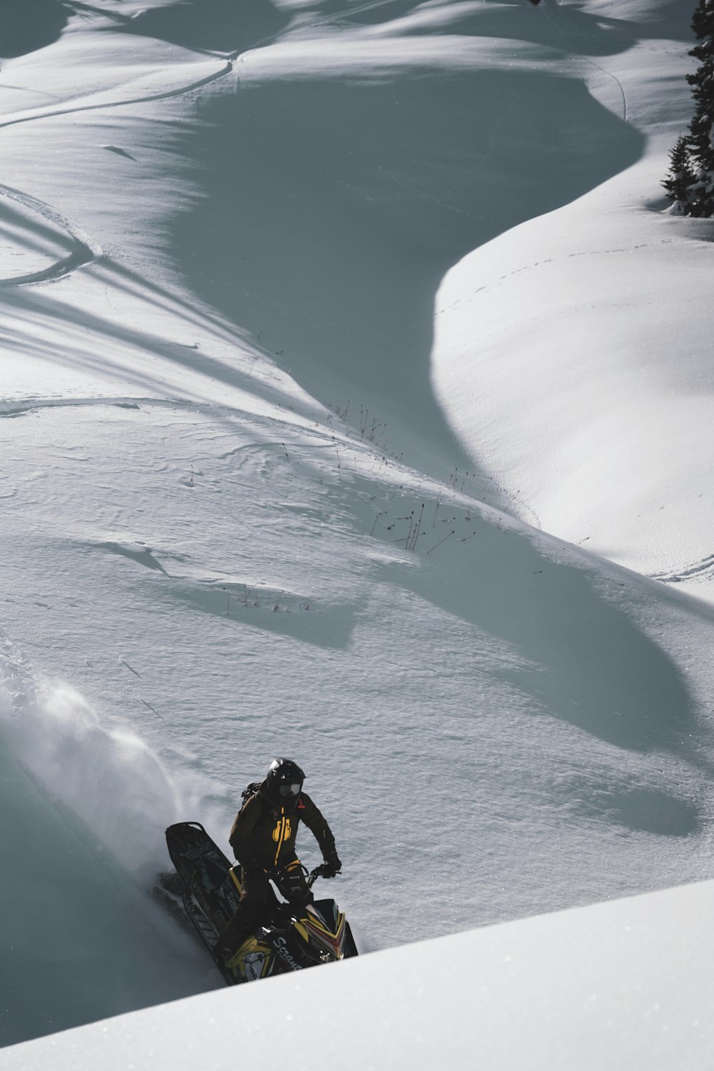 a man riding a snowmobile down a snow covered slope