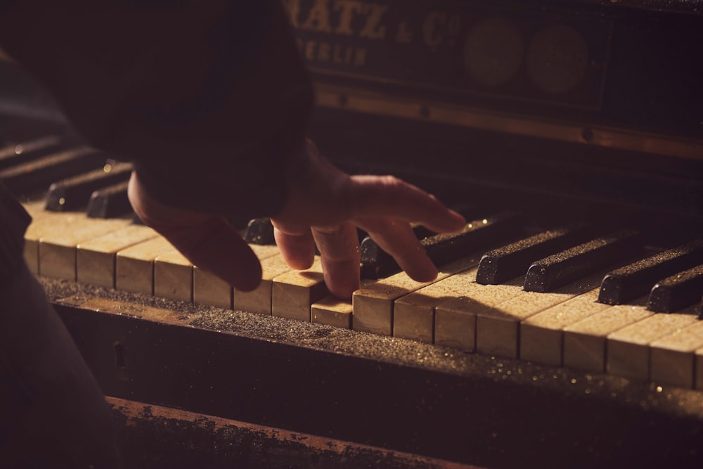 a person's hand on the keys of a piano