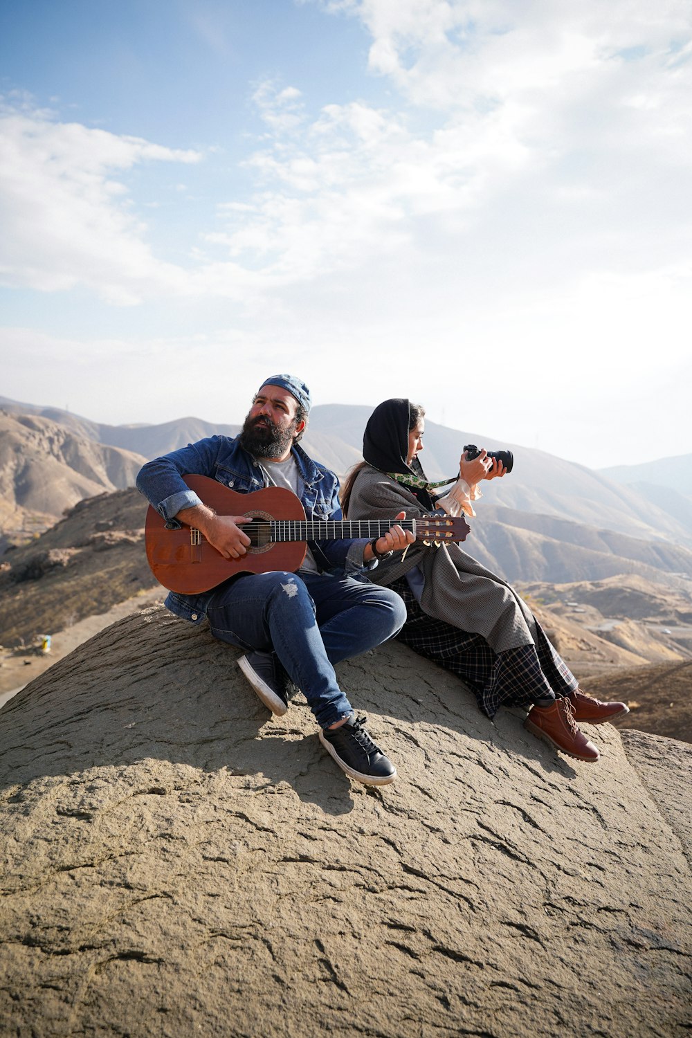 a man and a woman sitting on top of a mountain