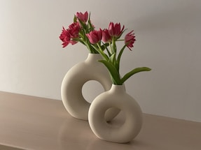 a white vase with pink flowers in it