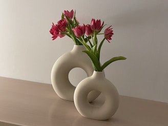 a white vase with pink flowers in it