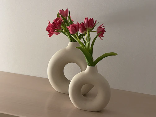 a white vase with pink flowers in it