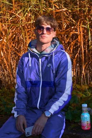 A fashionable person holding a phone with a stylish case and sipping a soft drink outdoors.