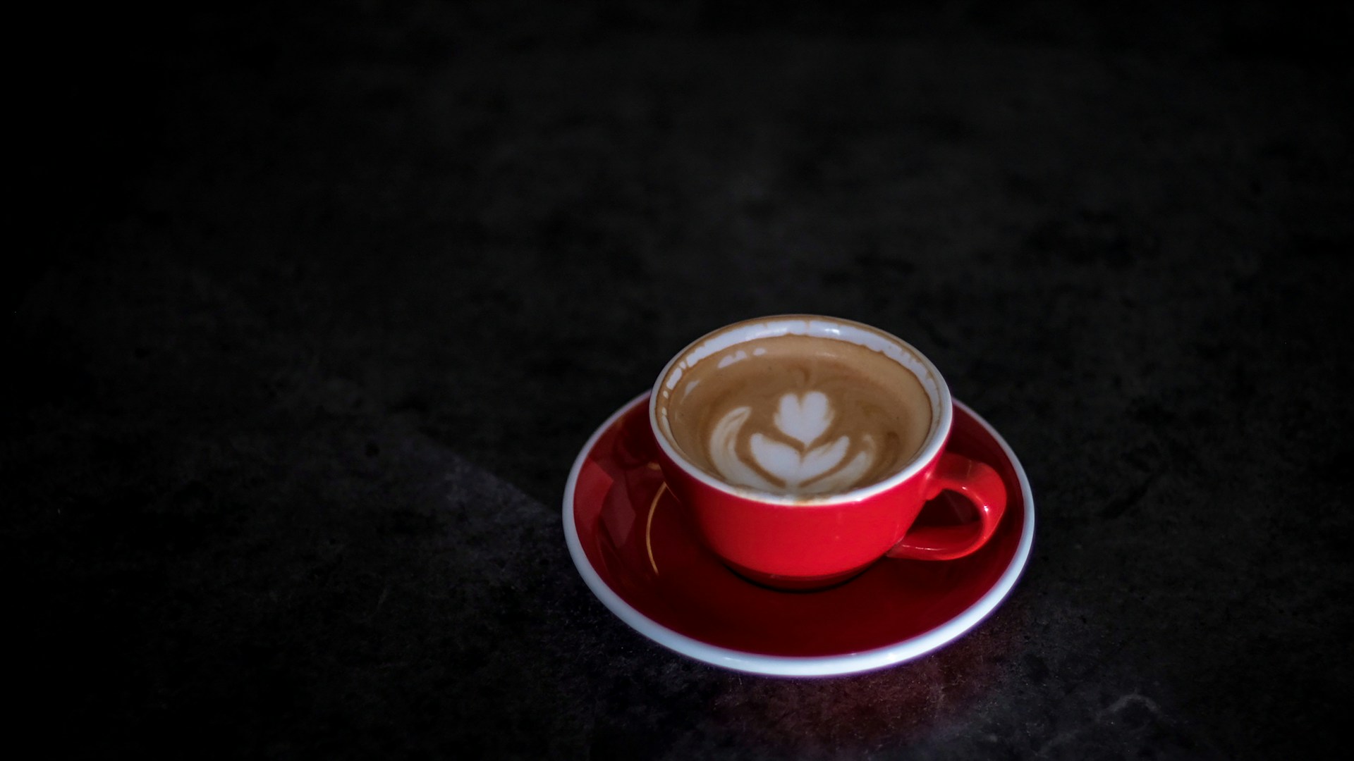 a cup of coffee on a saucer on a black table