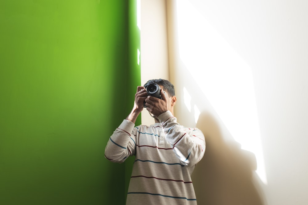 a man taking a picture of a green wall with a camera