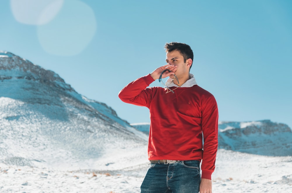 a man in a red sweater is drinking water