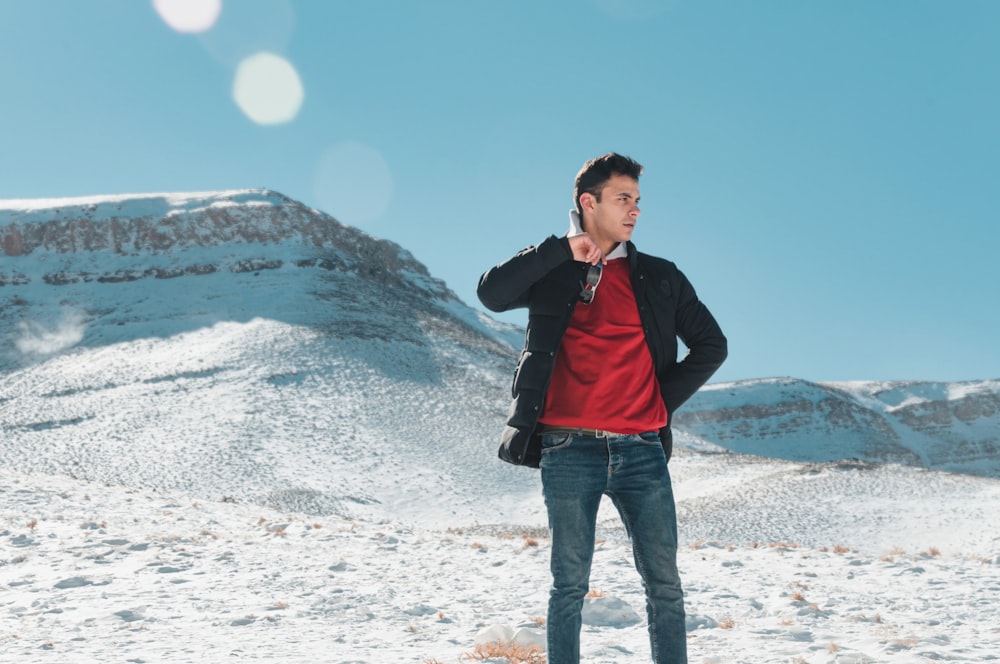 a man in a red shirt and black jacket standing in the snow