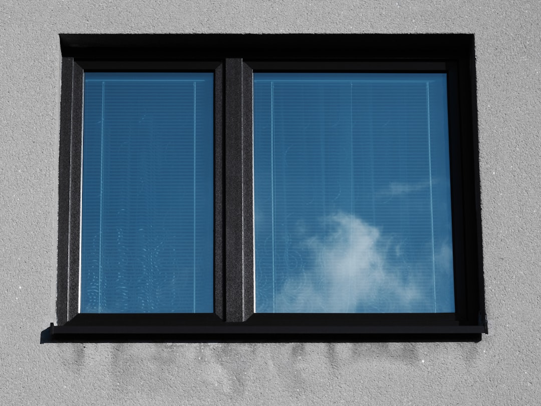 a window with a blue sky and clouds reflected in it,