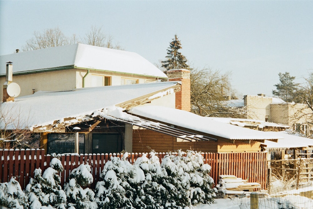 a house covered in snow next to a fence