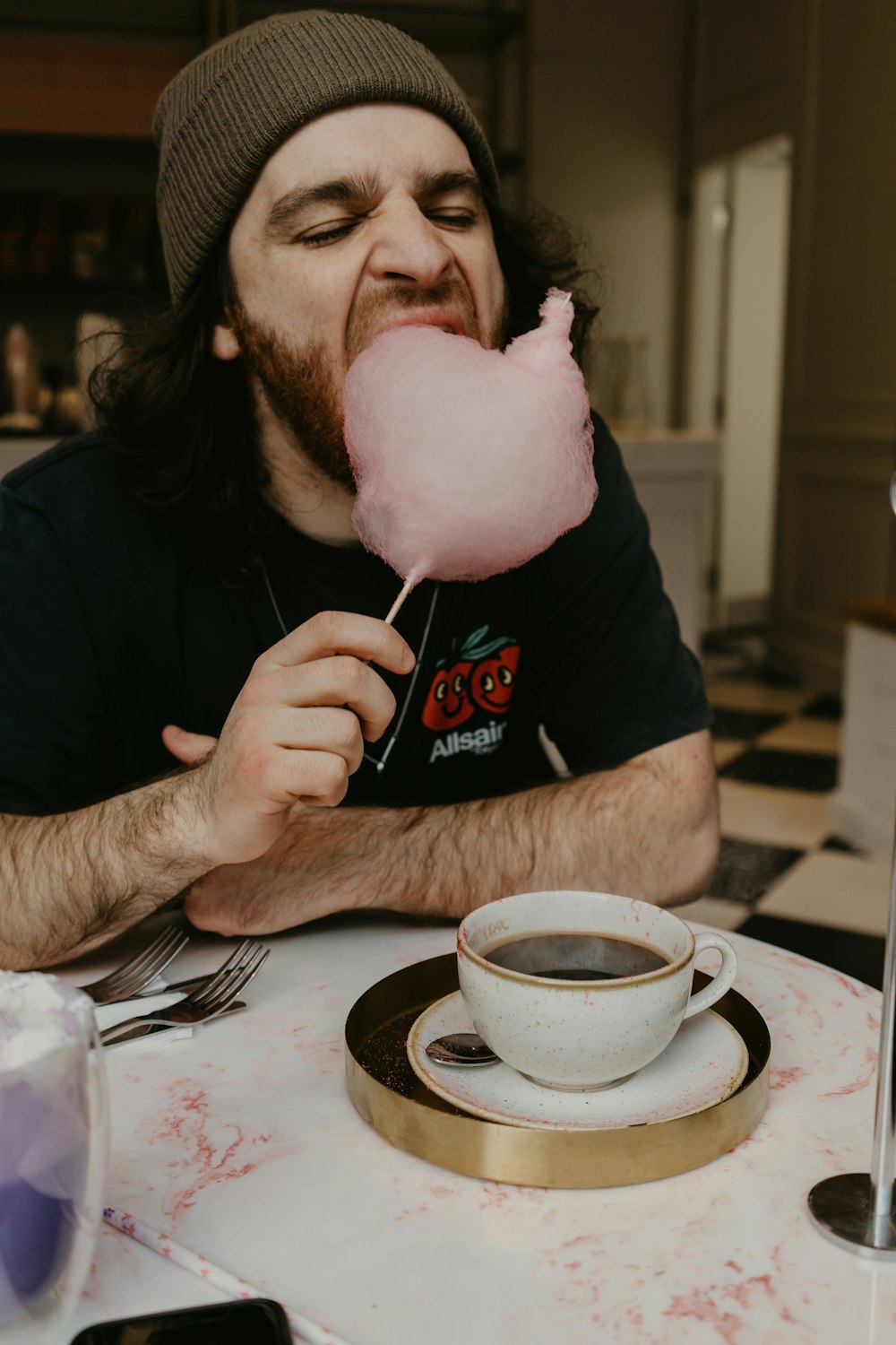 a man sitting at a table eating a pink lollipop