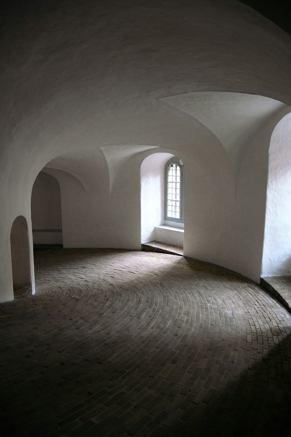an empty room with a brick floor and arched windows