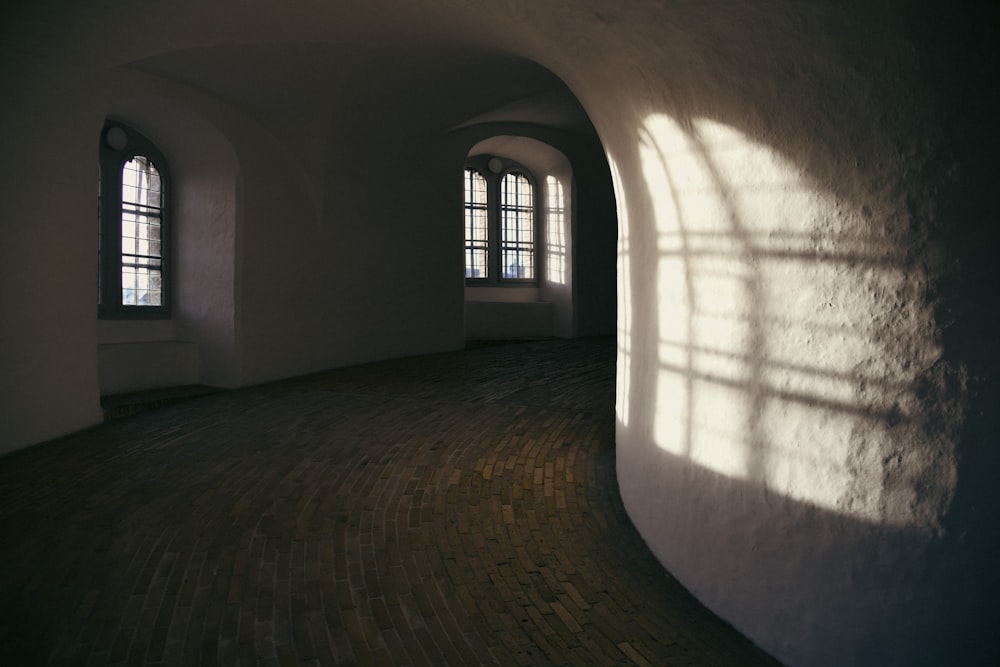 an empty room with three windows and a brick floor