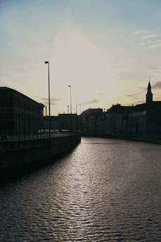 A serene urban waterway flowing gently through a cityscape at sunset, highlighting the harmony between nature and urban engineering.