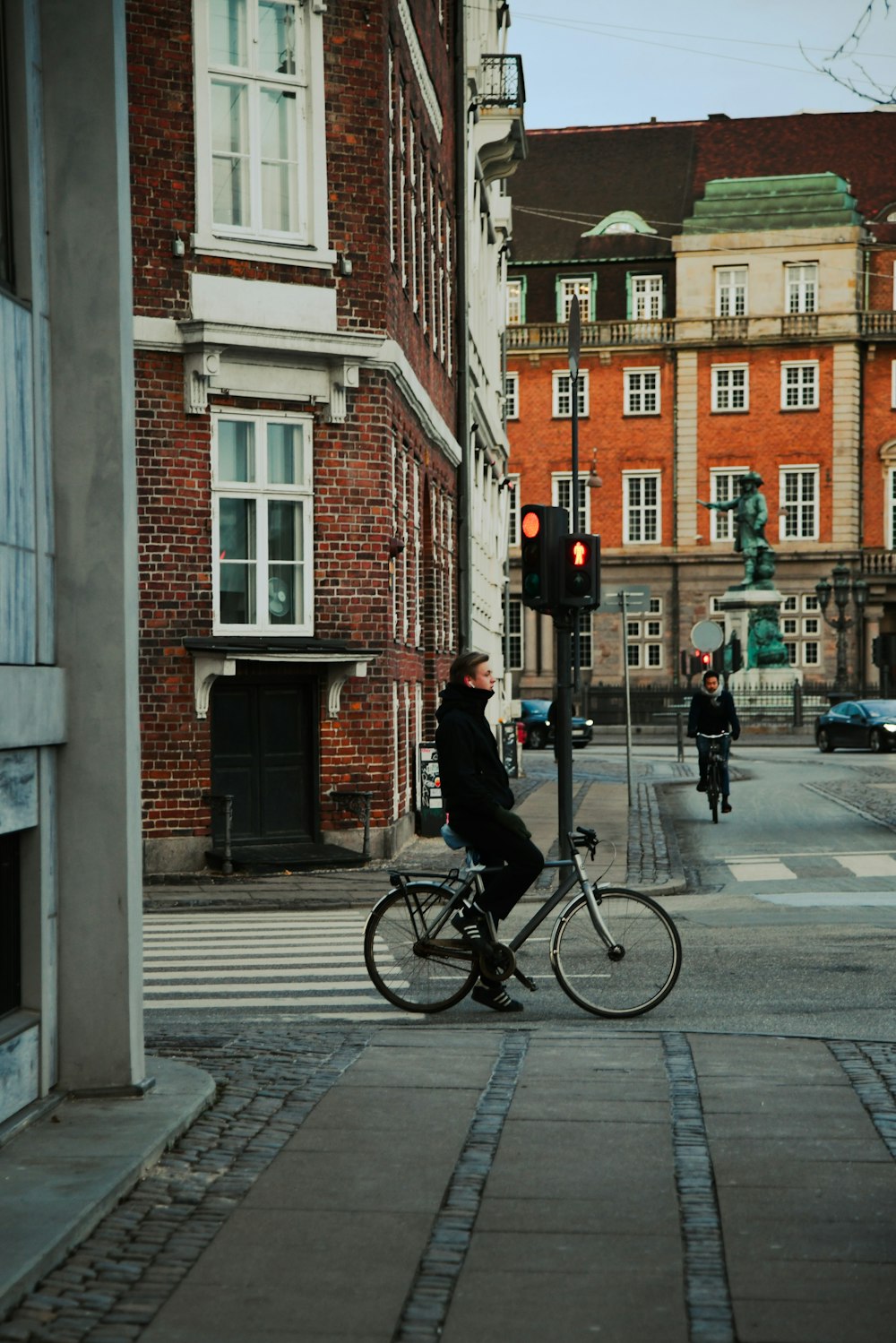 a man riding a bike down a street next to tall buildings