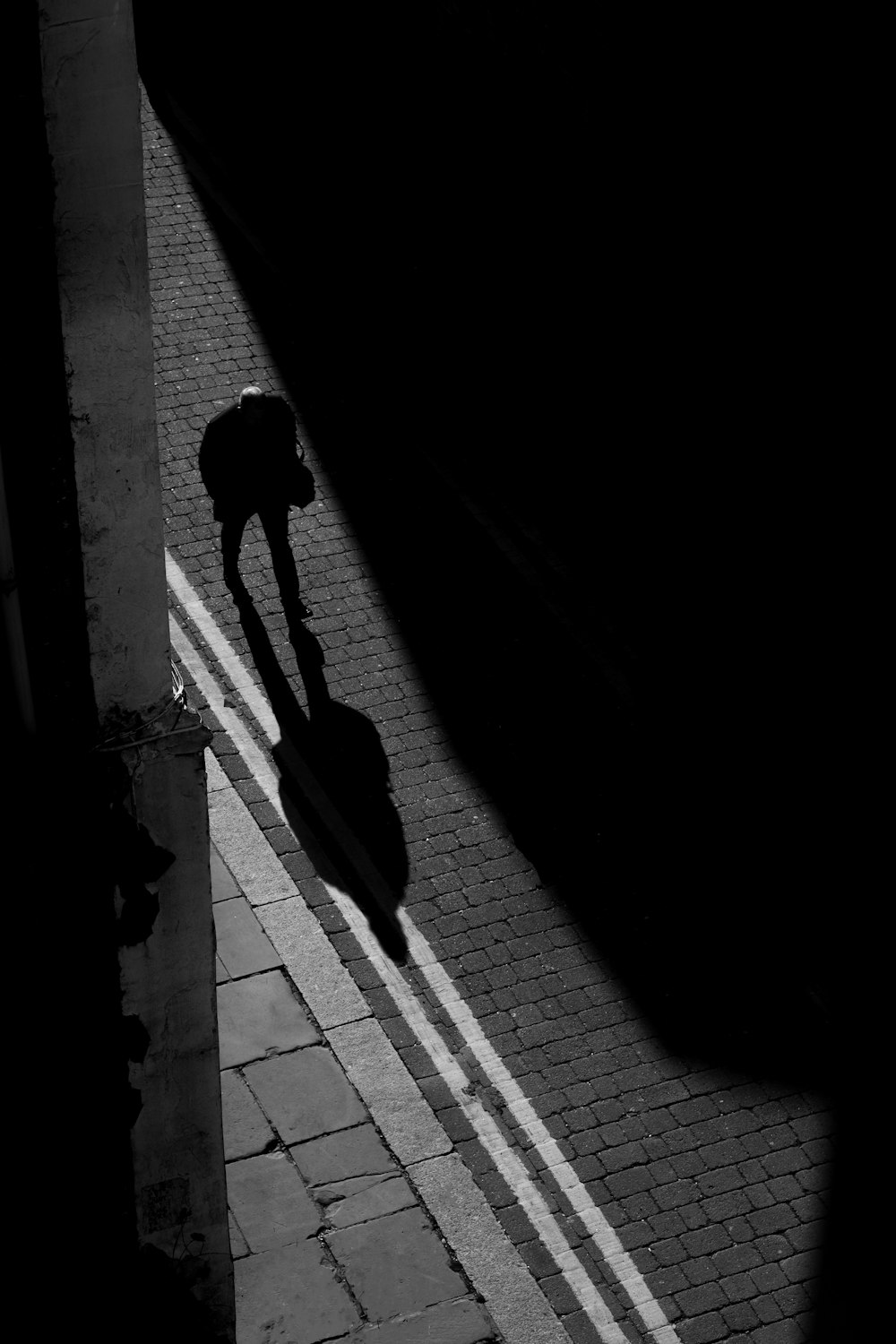 a shadow of a person walking down a street