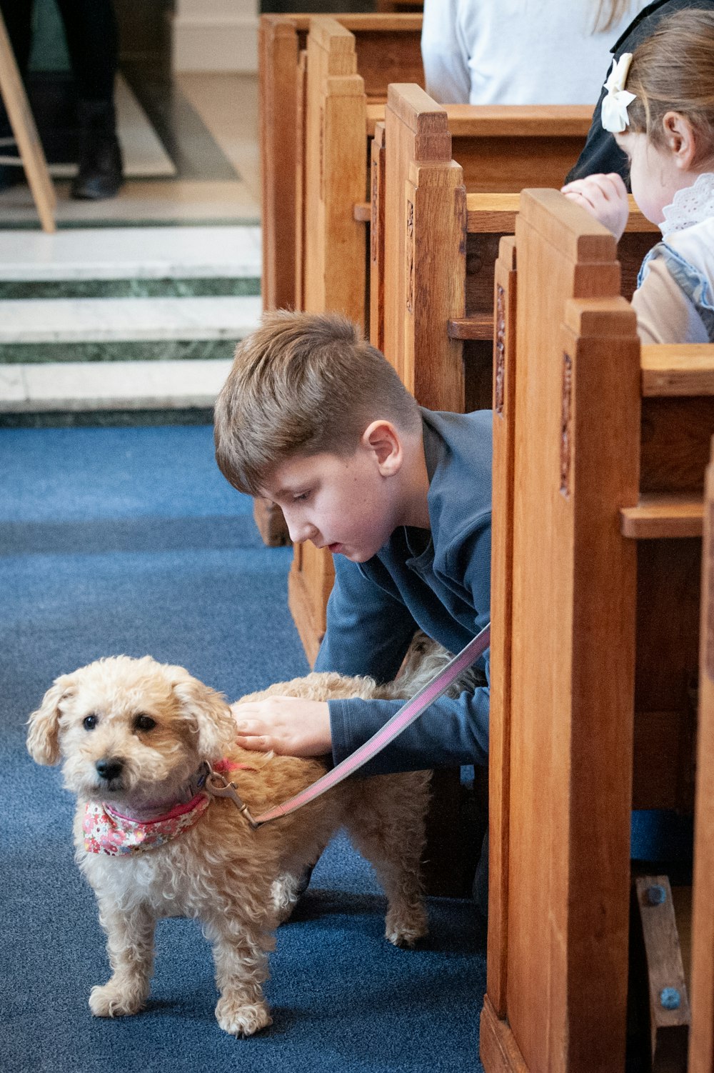 Ein kleiner Junge, der in einer Kirche einen Hund streichelt