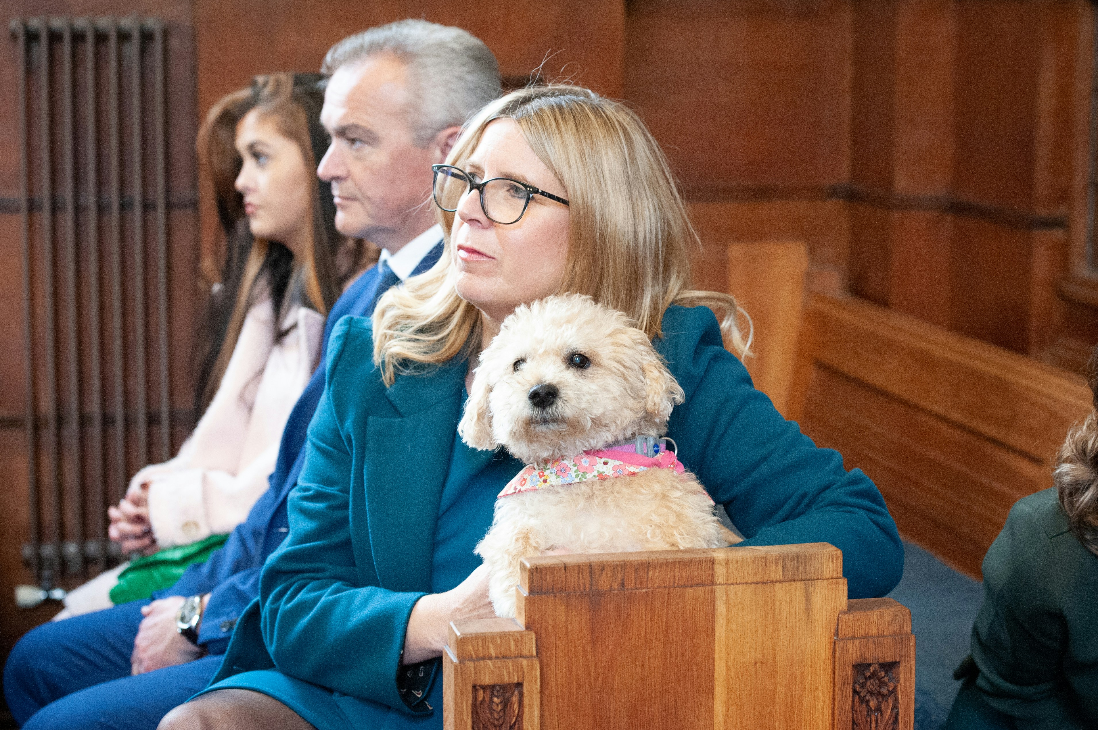 a woman sitting in a courtroom with a dog on her lap
