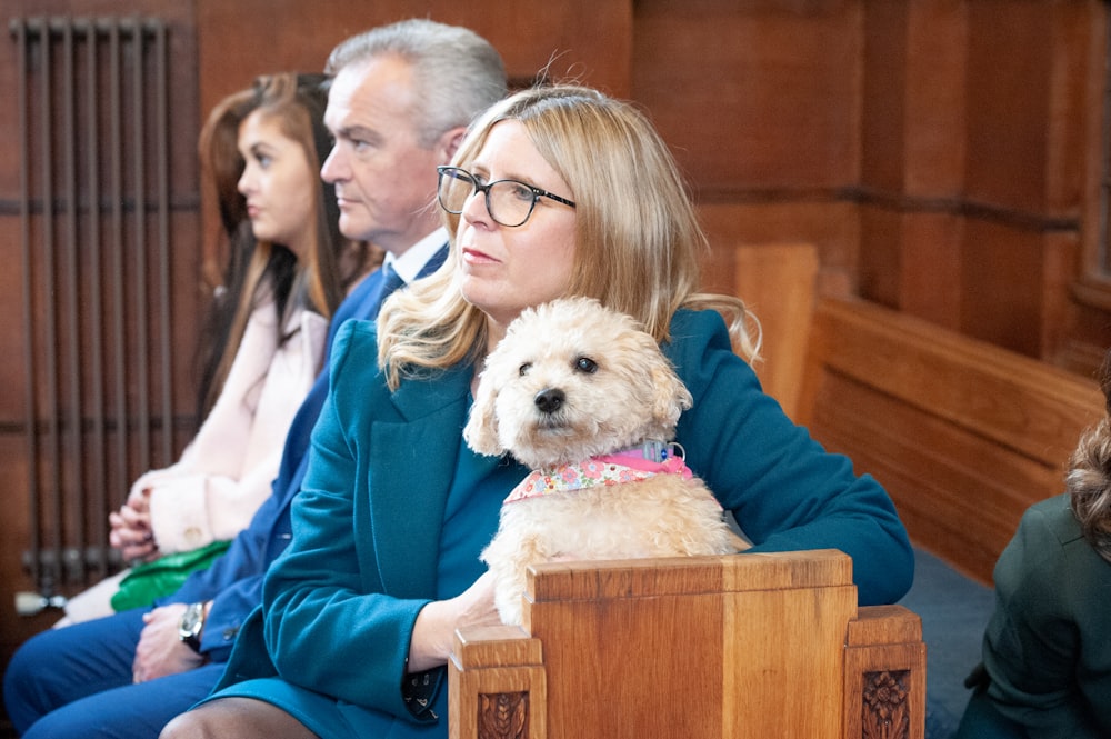 Eine Frau sitzt in einem Gerichtssaal mit einem Hund auf dem Schoß