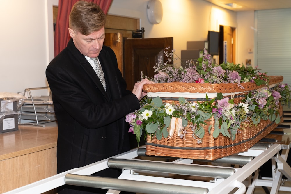 a man in a suit and tie holding a basket of flowers