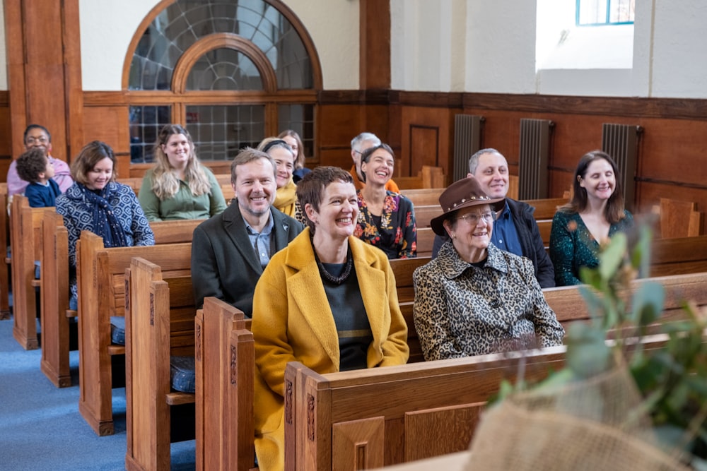 Eine Gruppe von Menschen, die in Kirchenbänken in einer Kirche sitzen
